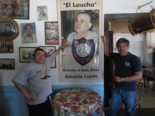 Tito y su hijo Cándido junto a la foto de don Antonio, fundador del Bar El Laucha que cumplió 64 años de vida.